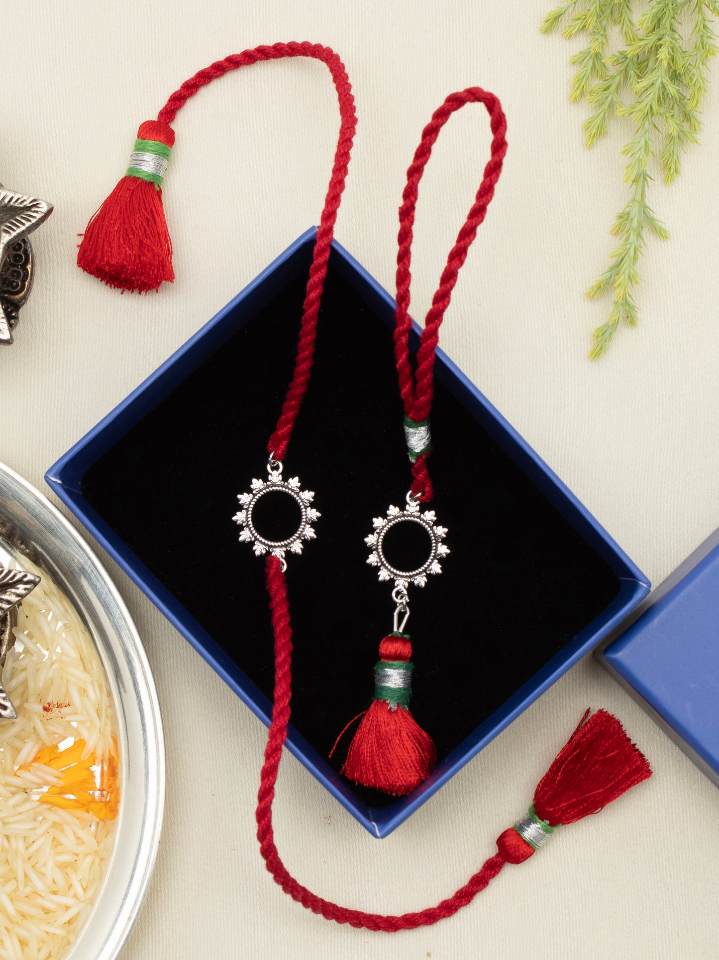 Floral rakhi and lumba pair displayed on a gift box with rice