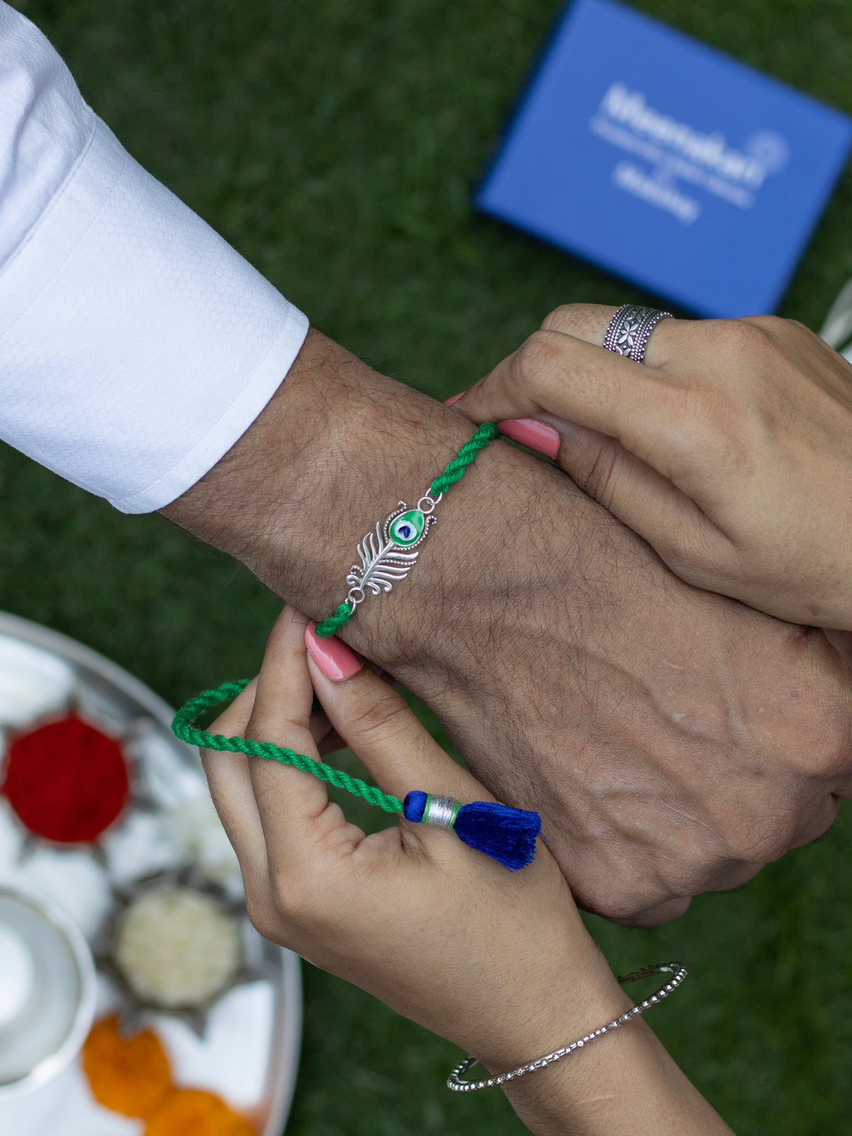 Peacock feather rakhi being tied on a wrist during the ceremony