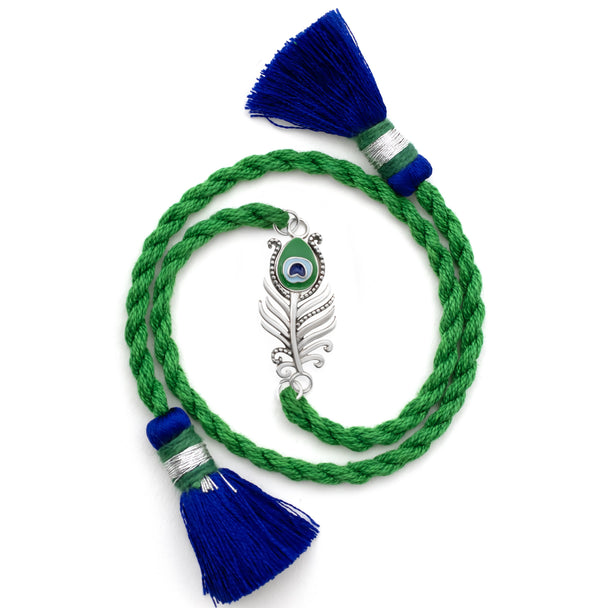 Silver peacock feather charm on a green braided rakhi with blue tassels