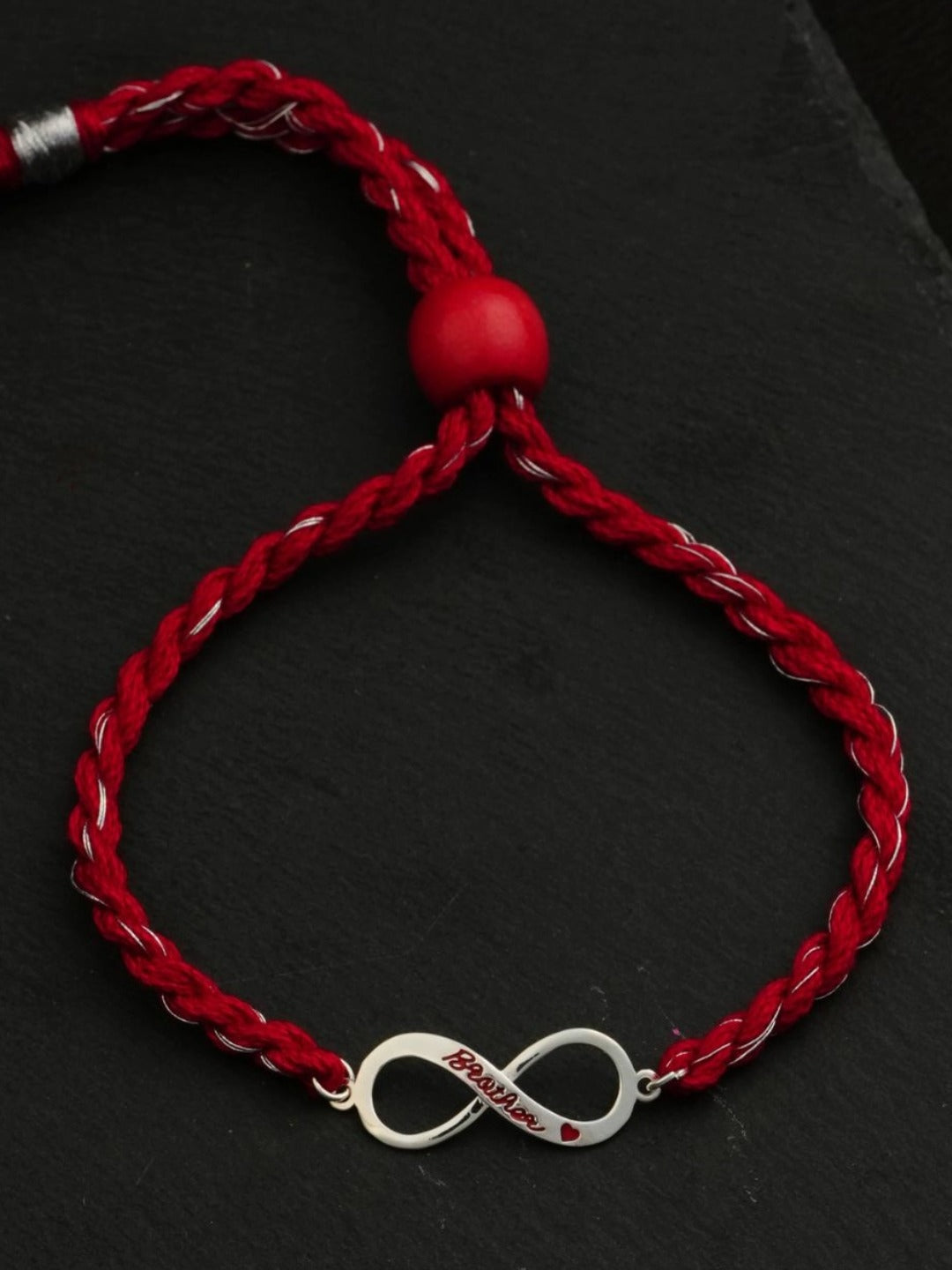 Close-up of the silver infinity charm on braided red thread