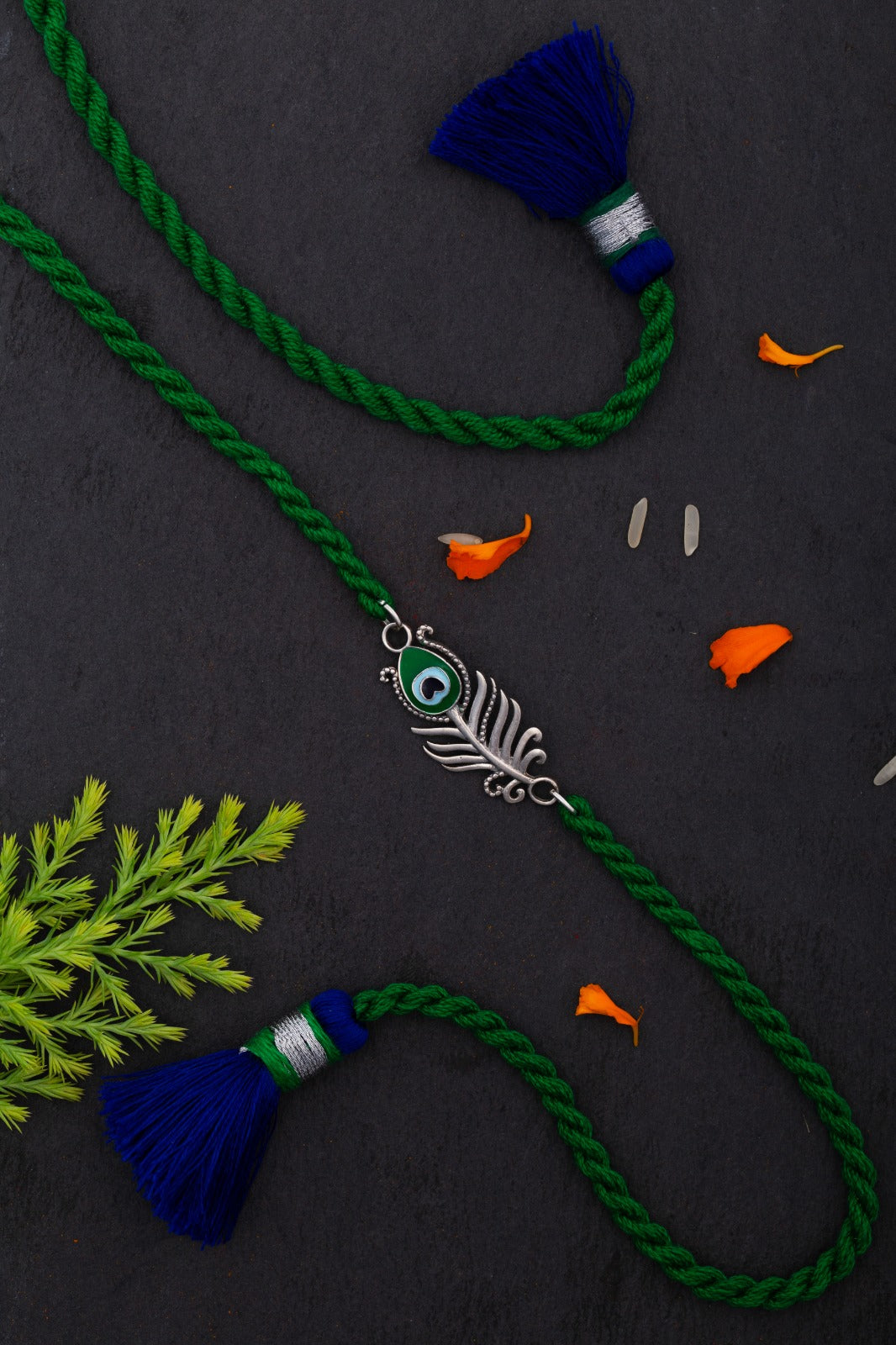 Peacock feather rakhi on a dark surface with a real peacock feather